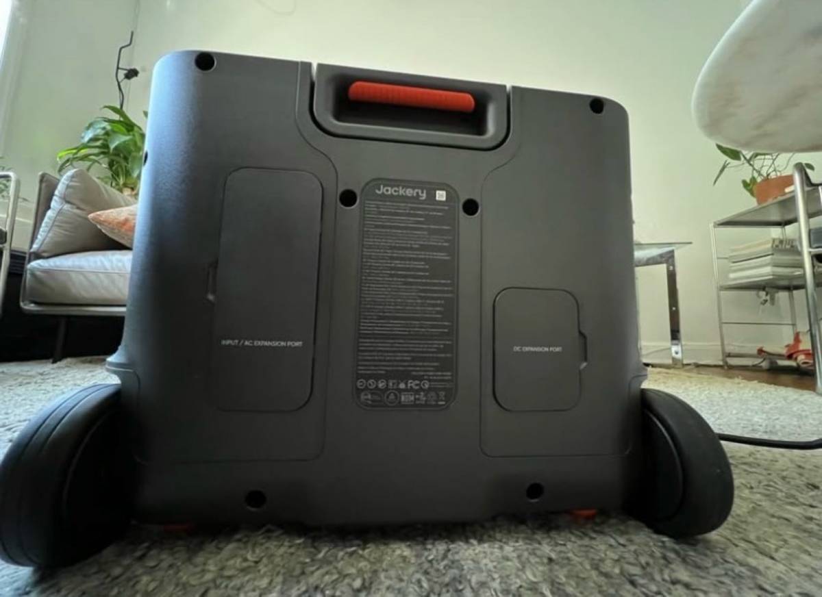 Jackery Explorer 2000 Plus rear view showing AC and DC expansion ports and rolling wheels in a home living room