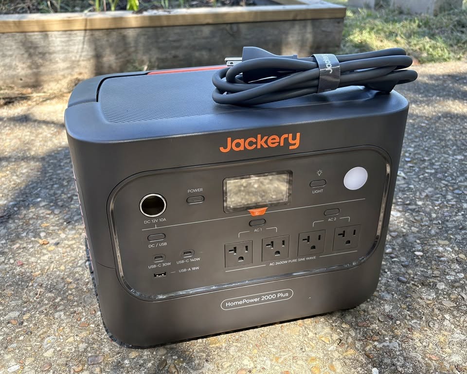 Jackery HomePower 2000 Plus v2 outdoors on a driveway with its AC charging cable